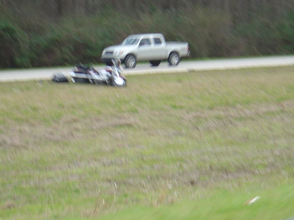 motorcycle on its side next to a silver pickup truck on a road