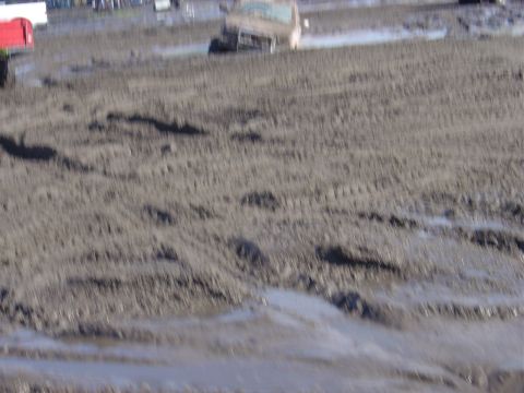 1987 Suzuki Samurai - A truck is stuck in a muddy area, with visible tire tracks in the foreground.