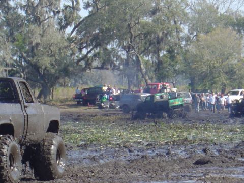1987 Suzuki Samurai - A muddy scene with several off-road vehicles participating in a bogging event.