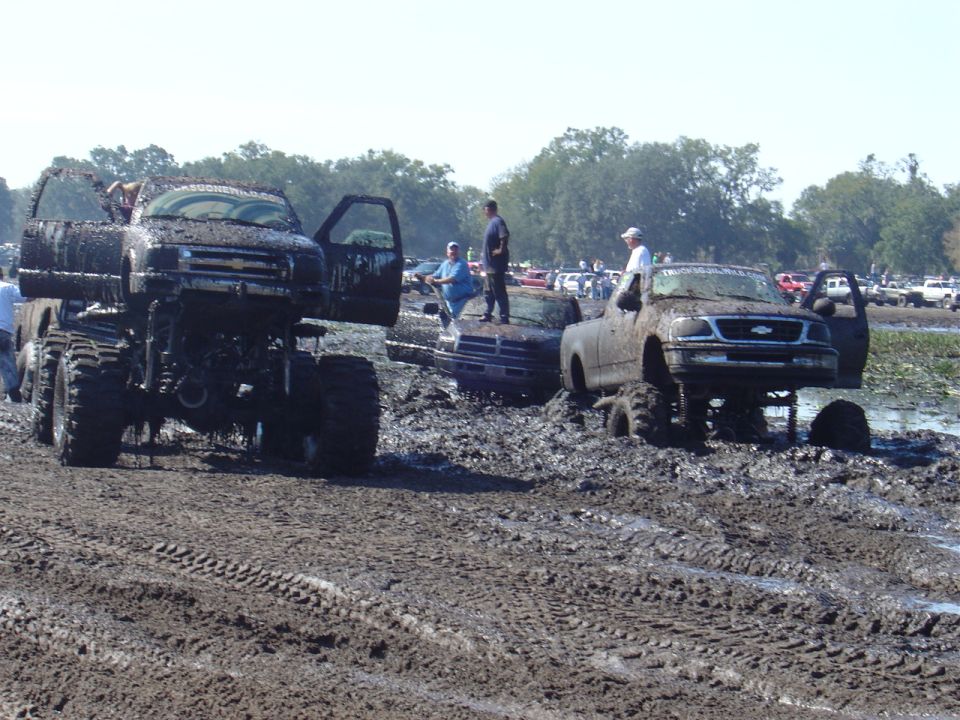 Mud bogging trucks with doors open stuck in mud