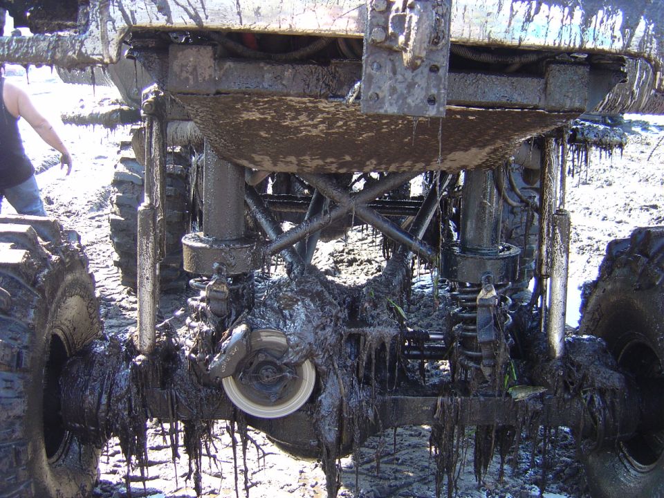 Mud-covered undercarriage of a lifted off-road vehicle with large tires