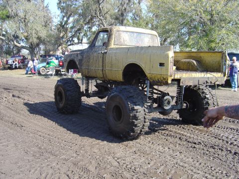 1987 Suzuki Samurai - This heavily modified pickup truck is caked in mud, suggesting it has been used for off-roading or mud bogging.