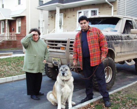 1989 Ford Bronco - A 1989 Ford Bronco is parked in a driveway with two people and a dog standing nearby.