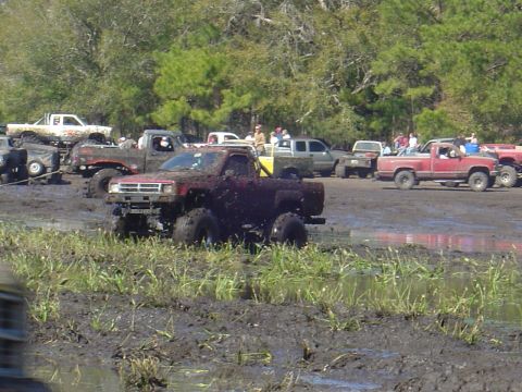 1987 Suzuki Samurai - Several trucks are stuck in the mud at an off-road event.