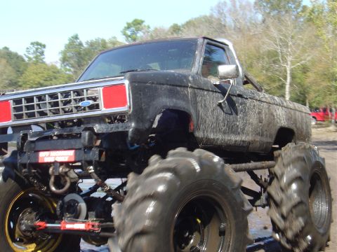 1987 Suzuki Samurai - This heavily modified truck is covered in mud, suggesting it has been used for off-road activities like mud bogging.