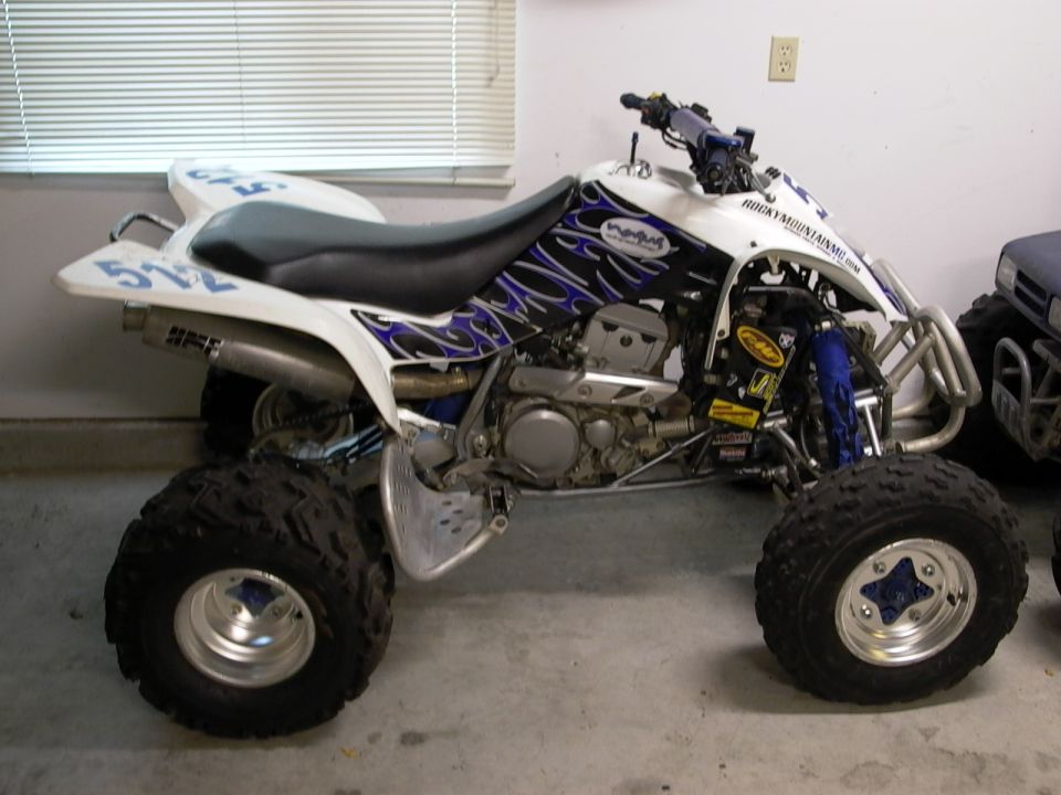 White sport quad ATV with blue flame graphics and '512' plates in a garage