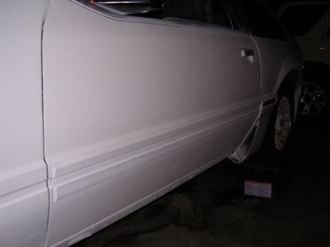 1988 Ford Mustang - Side profile of a white 1988 Ford Mustang, highlighting its door and lower body molding.
