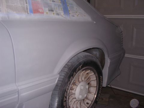 1988 Ford Mustang - The car is being prepped for paint, with newspaper covering the window area and primer applied to the body panels.