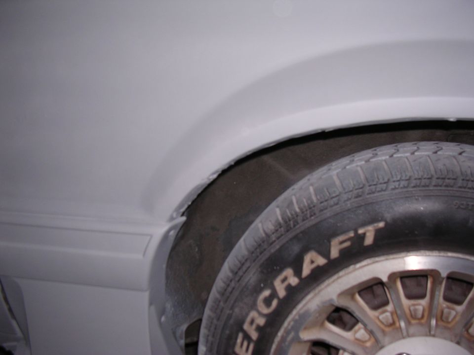 Close-up of a car's wheel well and tire with "SUPERMOTORS" visible on the tire