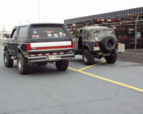 1989 Ford Bronco - A black 1989 Ford Bronco is parked next to a Jeep, viewed from the rear.