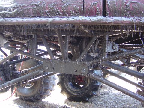 1987 Suzuki Samurai - Undercarriage of a heavily modified off-road vehicle covered in mud. Supermotors.net logo visible.