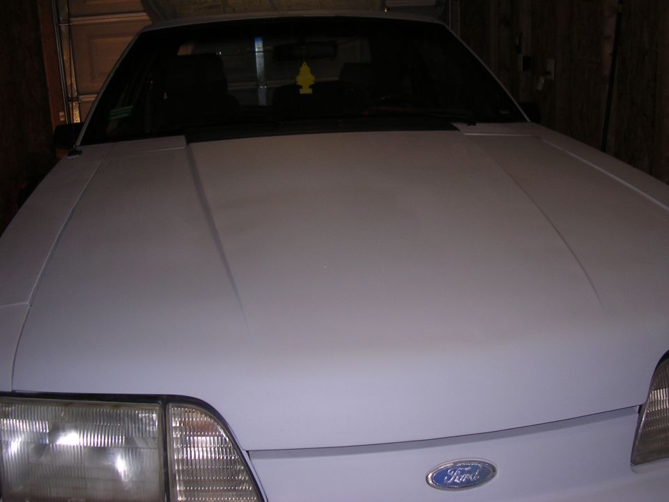 White car hood and headlight with a Supermotors logo visible