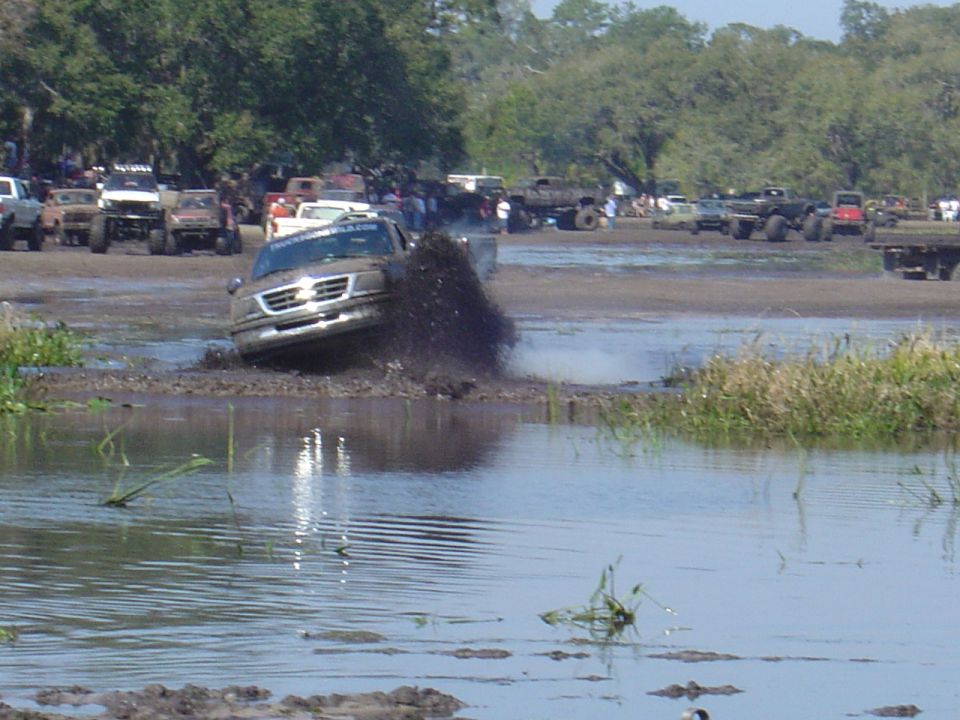 Silver SUV splashing through mud at an off-road event