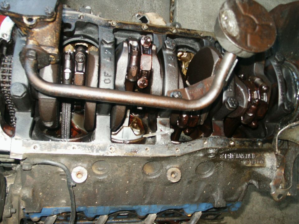 Engine block with crankshaft, connecting rods, and oil pump pickup tube visible; some parts are greasy