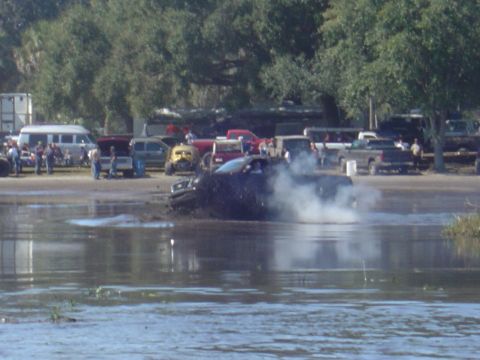 1987 Suzuki Samurai - Pickup truck stuck in mud during an event, with spectators and other vehicles in the background.