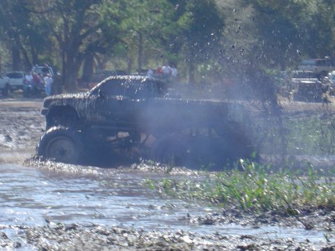 1987 Suzuki Samurai - A pickup truck navigates a muddy obstacle course, kicking up spray as it goes.