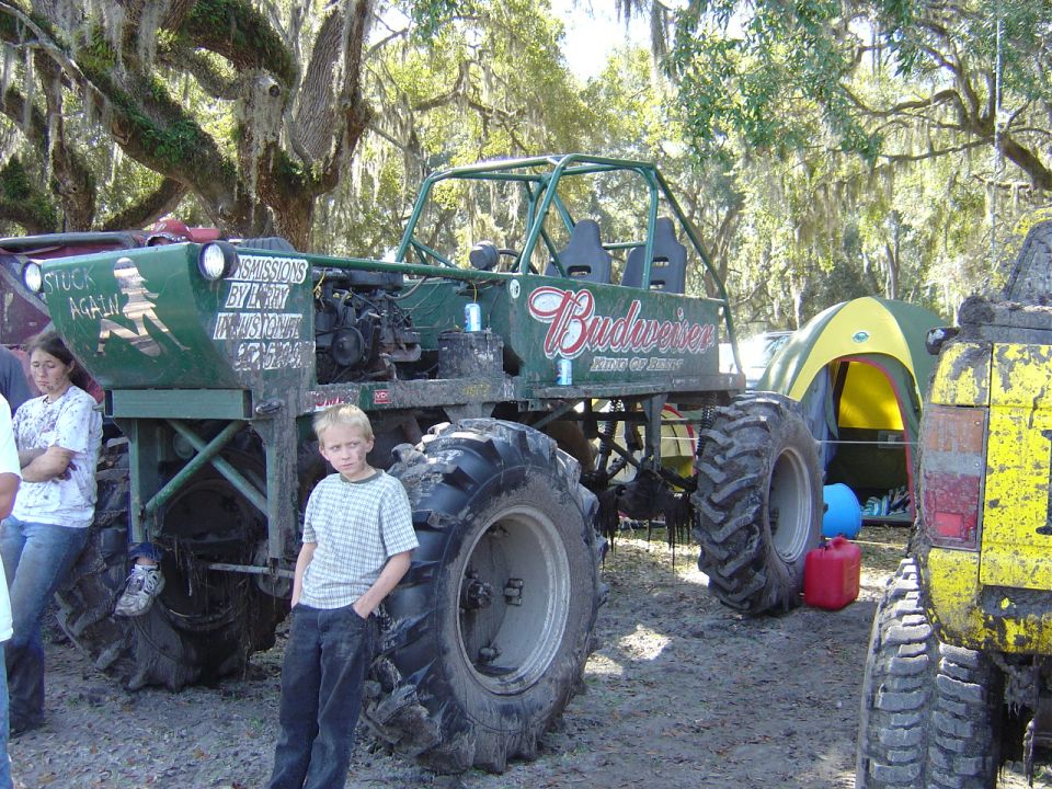 Custom green off-road vehicle with Budweiser logo and large tires. A boy stands in front. Another yellow vehicle is to the right