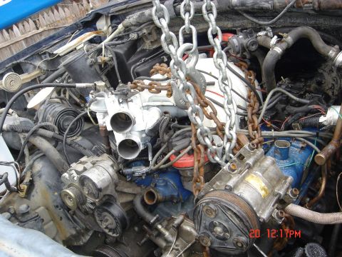 1991 Ford Bronco - Engine components, including carburetor and alternator, are suspended by chains, suggesting an engine rebuild or removal process.