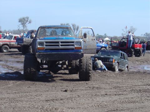 1987 Suzuki Samurai - Several off-road vehicles are stuck in the mud at an outdoor event.