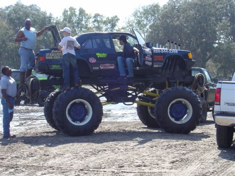 1987 Suzuki Samurai - A modified sedan body sits atop a lifted chassis with enormous tires, resembling a monster truck.