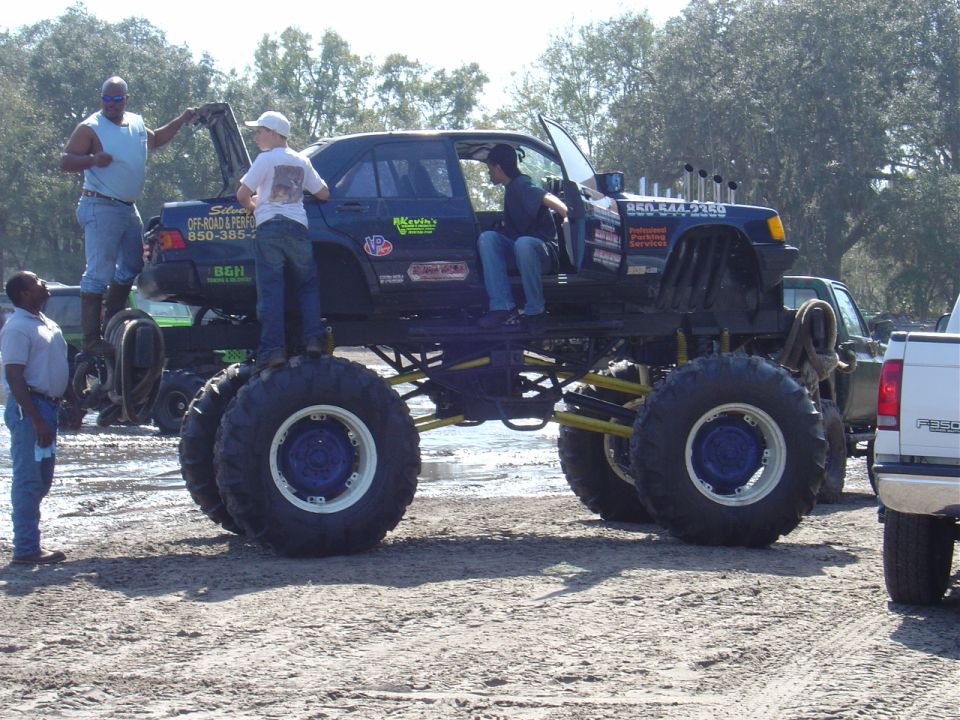 Monster truck with sedan body, lifted high on massive tires