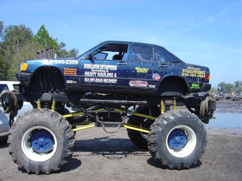 1987 Suzuki Samurai - This heavily modified sedan sits atop a massive suspension system and oversized tires, displaying numerous sponsor decals.