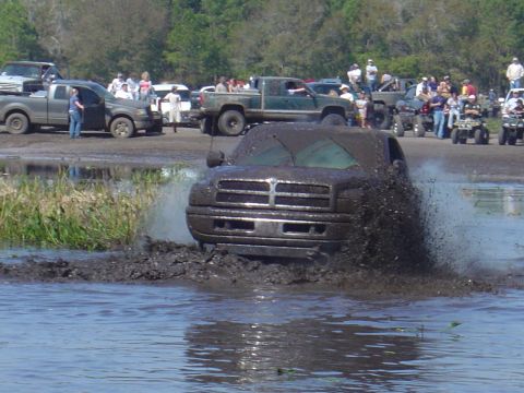 1987 Suzuki Samurai - A truck is stuck in the mud during an off-road event with spectators watching.