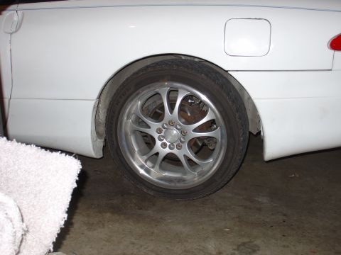 1993 Ford Probe - Close-up of a white car's rear wheel and fender area, showing aftermarket rims and a fuel filler door.
