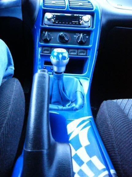 1994 Ford Probe - Interior view of a car a bright blue dashboard and a custom gear shift knob with a checkered flag decal on the center console.
