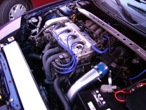 1994 Ford Probe - The engine bay features blue spark plug wires and an aftermarket intake system, with another vehicle visible in the background.