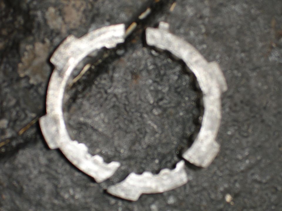 Broken metal ring with internal notches, appears to be a vehicle part