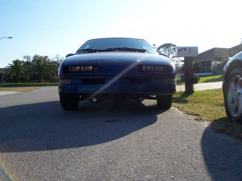 1994 Ford Probe - A dark blue coupe is parked in front of a house on a sunny day, with another vehicle partially visible.