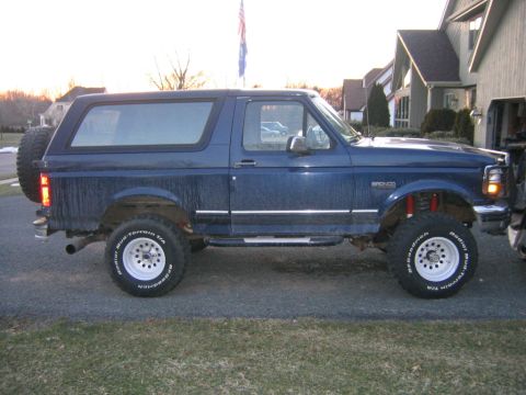 1994 Ford Bronco - This lifted blue Ford Bronco has aftermarket wheels and tires, and a spare tire mounted on the rear.