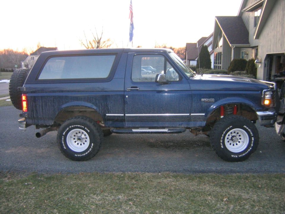 Blue lifted Ford Bronco passenger-side profile with mud-terrain tires and rear spare