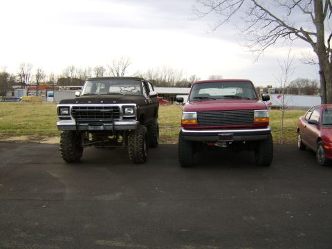 1978 Ford Bronco - A lifted black 1978 Ford Bronco is parked next to a red pickup truck.