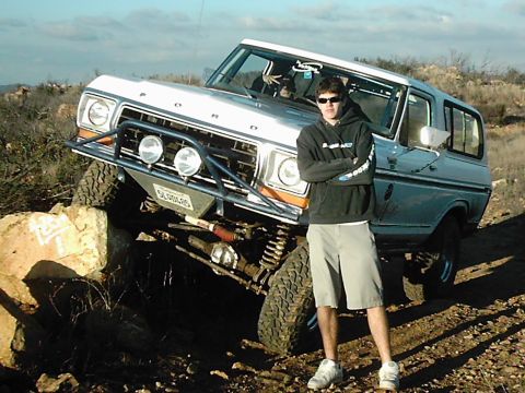 1978 Ford Bronco - A person poses with a modified Ford Bronco as it navigates a rocky trail.