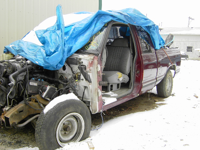Maroon 1997 Chevrolet C/K Pickup, 3/4 front view, covered with a blue tarp