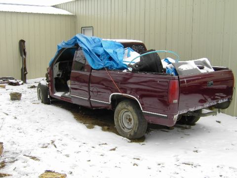 1997 Chevrolet C/K Pickup - Maroon 1997 Chevrolet C/K Pickup truck partially covered by a blue tarp in a snowy outdoor setting.