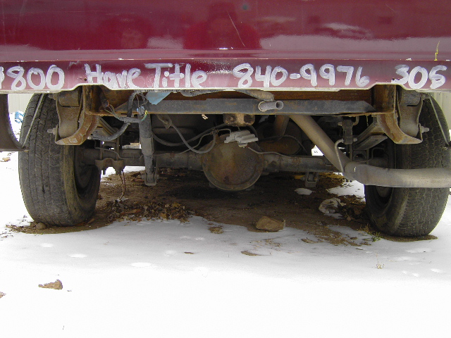 Maroon pickup truck rear axle with white text '1800 Have Title 840-9976 305' written on the frame