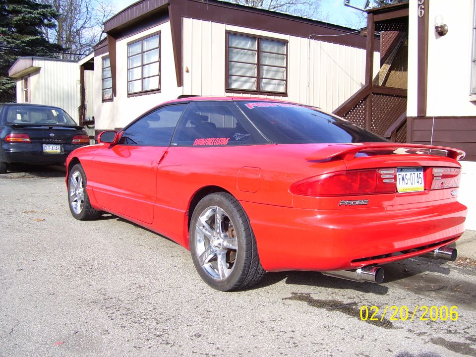 Red 1994 Ford Probe parked outside a trailer home, with another car in the background