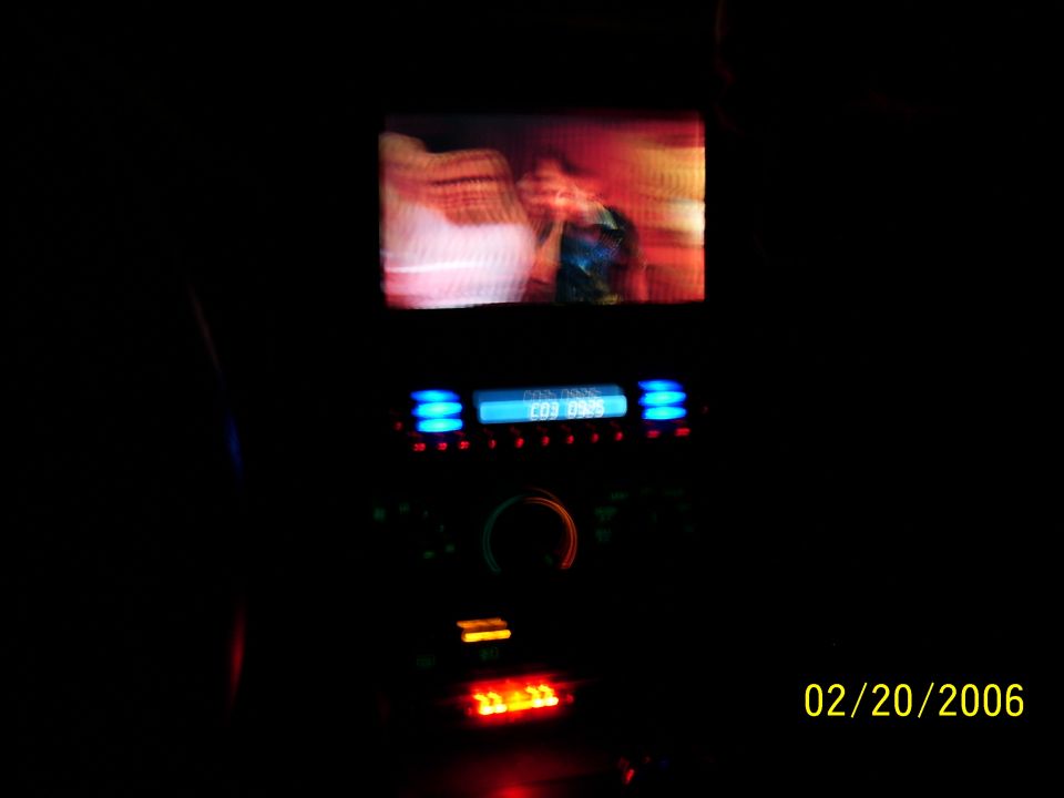Car interior showing a small screen above a car stereo with blue illuminated display. Date stamp 02/20/2006