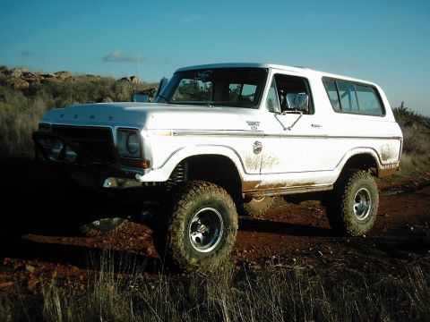 1978 Ford Bronco - A white 1978 Ford Bronco is seen off-road under a clear blue sky.