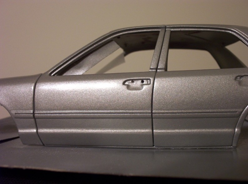 Silver car side view showing door handle and window frame. Supermotors.net logo visible