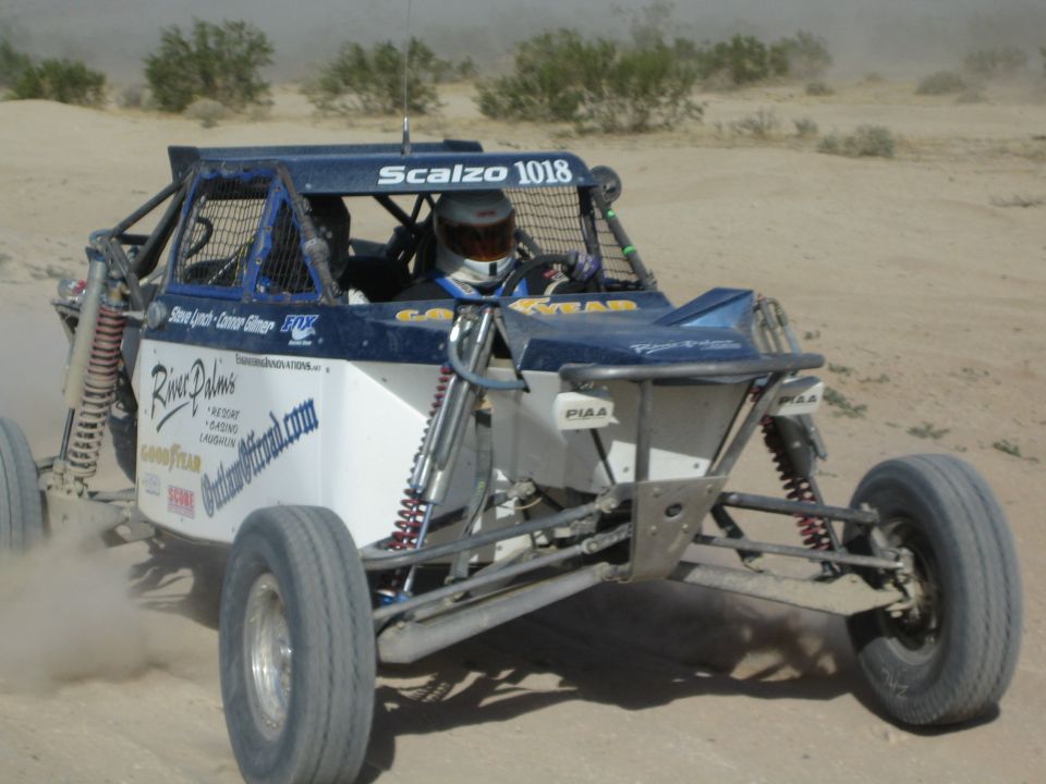 Blue and white off-road race buggy number 1018 with helmeted driver