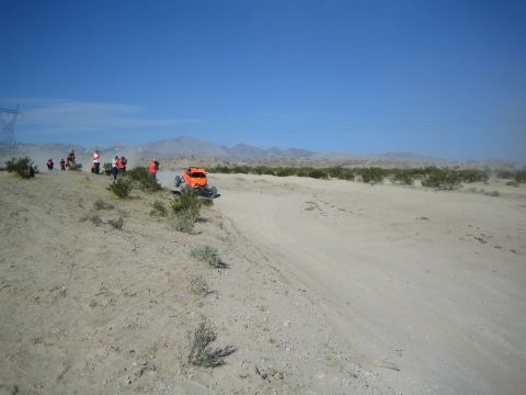 Orange off-road buggy passing spectators on a desert course