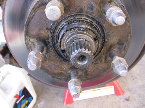 1987 Ford Bronco - Wheel hub assembly detail, showing rotor and lug nuts. Oil bottle in background.