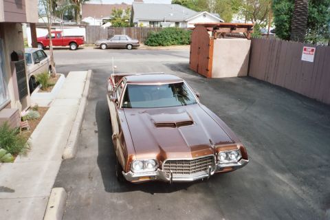 1972 Ford Ranchero - A brown 1972 Ford Ranchero is parked in a driveway, with other vehicles and houses in the background.