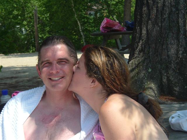 Couple on a beach with a tree and picnic table in the background