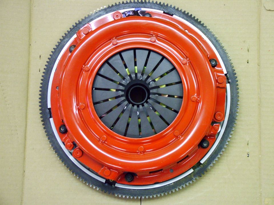 Orange clutch assembly with gray friction disc and toothed flywheel ring