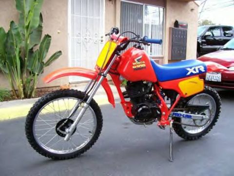 1972 Ford Ranchero - A Honda XR dirt bike is parked in front of a building, with other vehicles visible in the background.